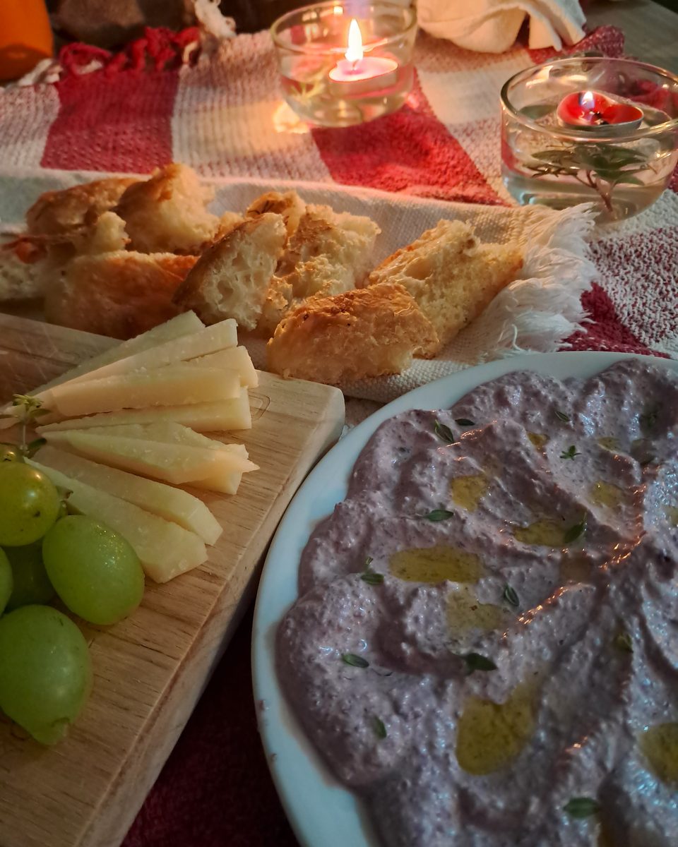 Patê servido num prato, com pão, queijo e uvas ao lado.